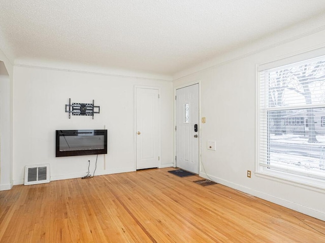 foyer featuring hardwood / wood-style flooring, a textured ceiling, and heating unit