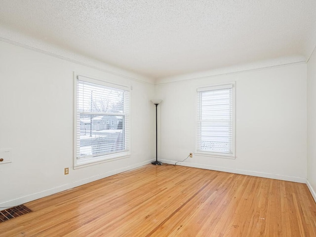 unfurnished room featuring light hardwood / wood-style flooring and a textured ceiling