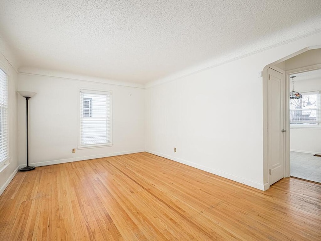 spare room with a textured ceiling and light wood-type flooring