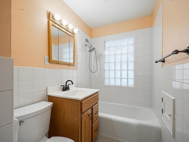 full bathroom with tile walls, vanity, tiled shower / bath, and toilet