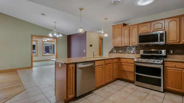 kitchen featuring sink, appliances with stainless steel finishes, hanging light fixtures, vaulted ceiling, and kitchen peninsula