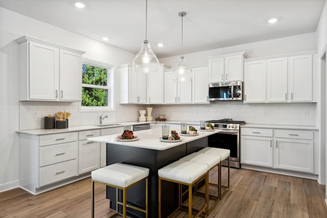 kitchen with appliances with stainless steel finishes, a kitchen breakfast bar, and white cabinets