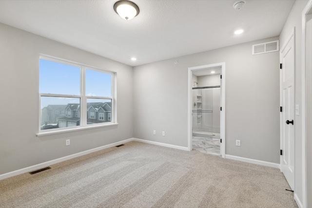 unfurnished bedroom with light carpet and connected bathroom