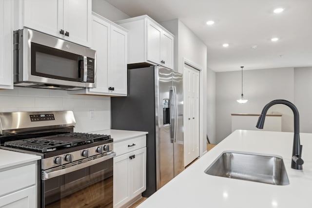 kitchen featuring a sink, stainless steel appliances, light countertops, and pendant lighting