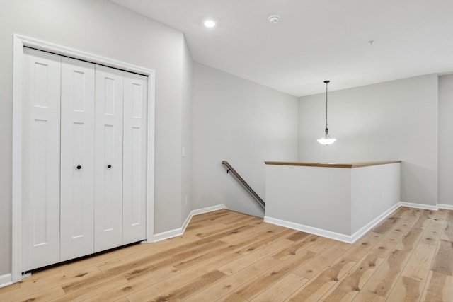 hallway featuring recessed lighting, baseboards, light wood-style flooring, and an upstairs landing