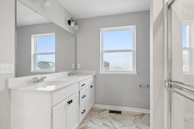 bathroom featuring marble finish floor, double vanity, a sink, and baseboards