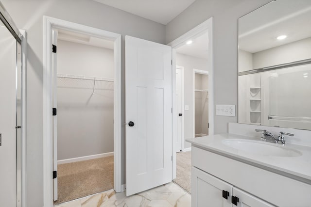 full bathroom with a walk in closet, marble finish floor, vanity, a shower stall, and baseboards