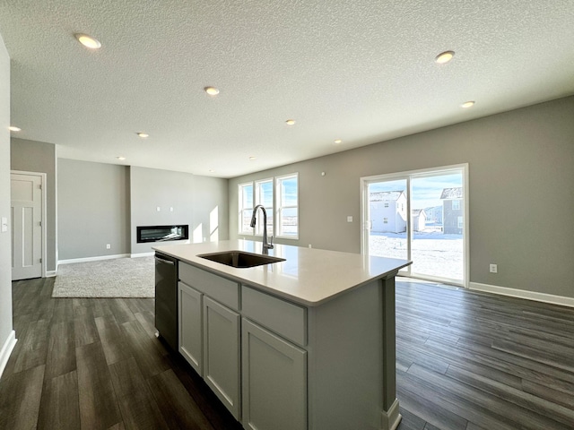 kitchen featuring dark hardwood / wood-style floors, sink, a kitchen island with sink, stainless steel dishwasher, and a textured ceiling