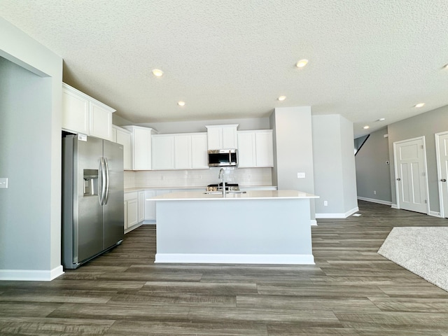 kitchen with tasteful backsplash, stainless steel appliances, an island with sink, and white cabinets