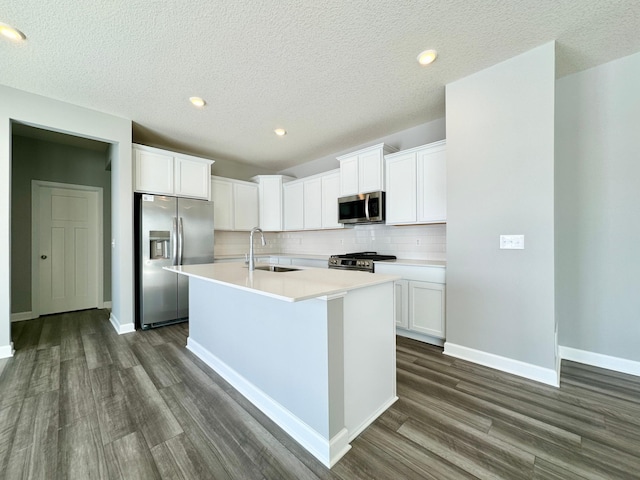 kitchen featuring sink, tasteful backsplash, appliances with stainless steel finishes, a kitchen island with sink, and white cabinets