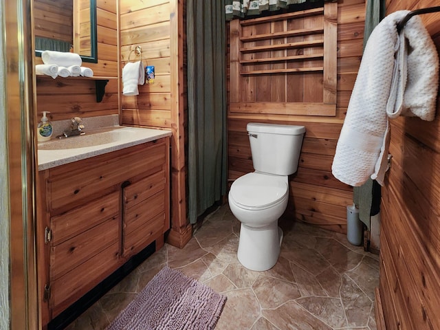 bathroom featuring vanity, toilet, and wood walls