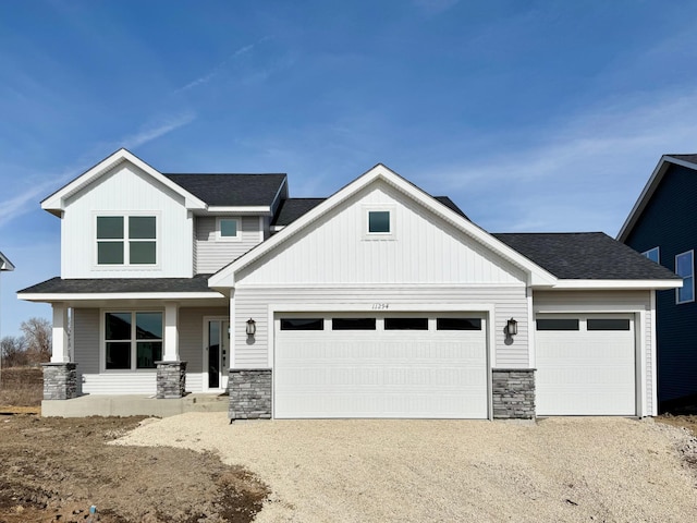 view of front of property featuring stone siding, dirt driveway, a porch, and an attached garage