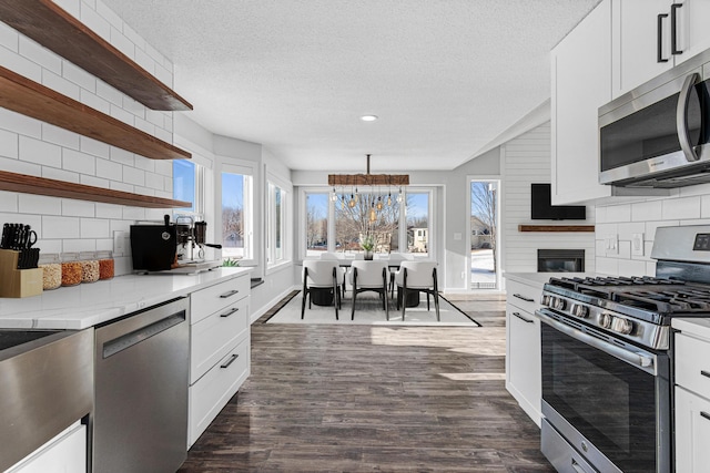 kitchen featuring a textured ceiling, stainless steel appliances, white cabinets, open shelves, and dark wood finished floors