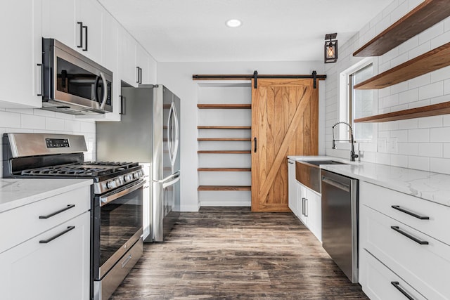 kitchen with dark wood-style floors, a barn door, appliances with stainless steel finishes, and open shelves