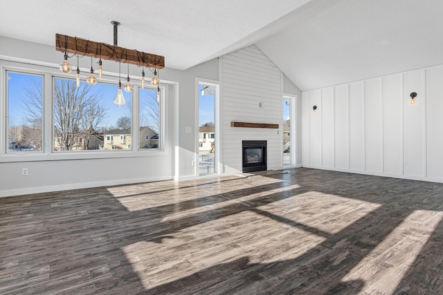 unfurnished living room featuring a large fireplace, baseboards, lofted ceiling, wood finished floors, and a textured ceiling