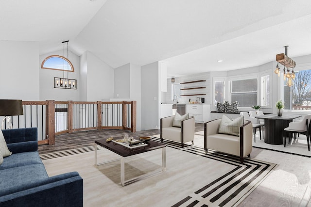 living room featuring high vaulted ceiling, a notable chandelier, and wood finished floors