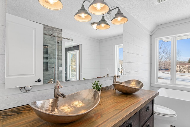 full bath with a freestanding bath, double vanity, a stall shower, and a sink