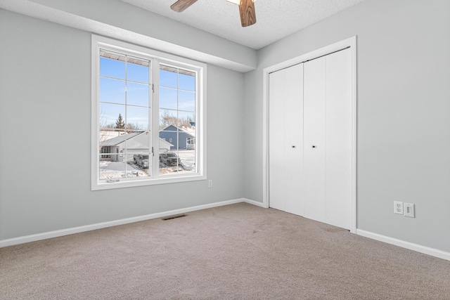 unfurnished bedroom featuring a textured ceiling, carpet floors, visible vents, baseboards, and a closet