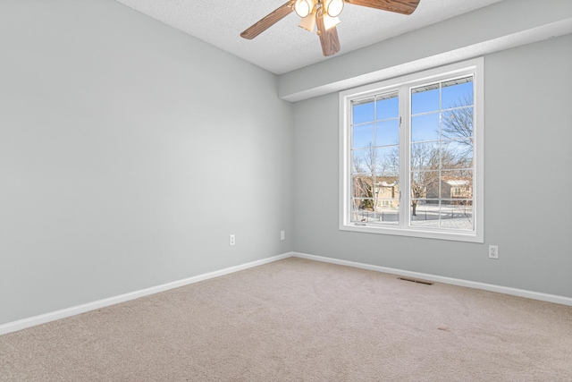 carpeted spare room featuring a ceiling fan, visible vents, a textured ceiling, and baseboards