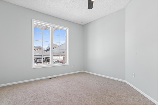 unfurnished room with carpet, visible vents, a ceiling fan, a textured ceiling, and baseboards