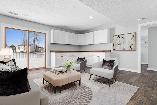 living room featuring visible vents, dark wood finished floors, a textured ceiling, and baseboards