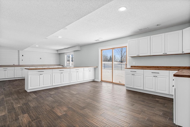 kitchen featuring dark wood-style flooring, recessed lighting, butcher block counters, white cabinets, and a textured ceiling