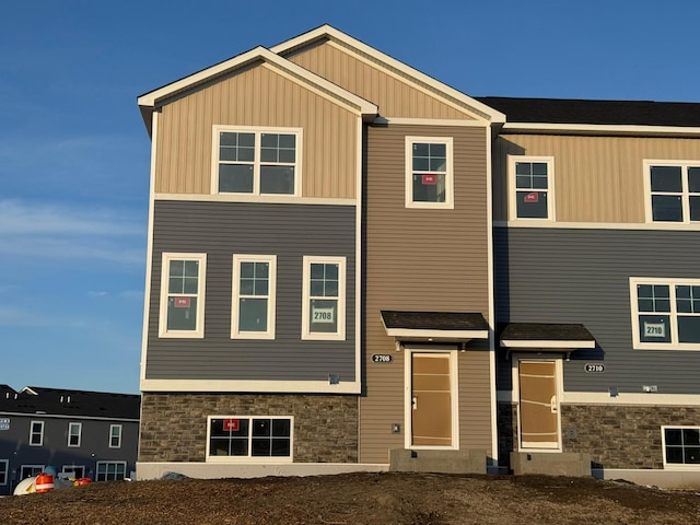 view of front facade featuring board and batten siding, entry steps, and stone siding