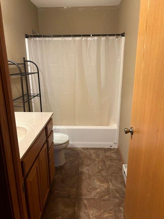 full bathroom featuring shower / tub combo with curtain, vanity, toilet, and a baseboard radiator