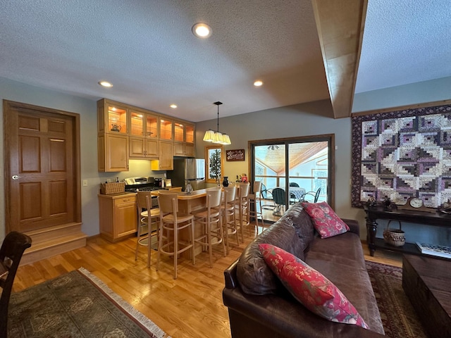 living area with light wood-type flooring, a textured ceiling, and recessed lighting