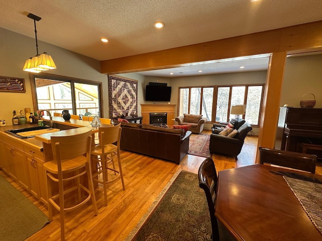 dining area with a fireplace, recessed lighting, a textured ceiling, and light wood-type flooring