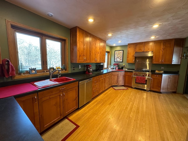 kitchen featuring brown cabinets, plenty of natural light, under cabinet range hood, stainless steel appliances, and a sink