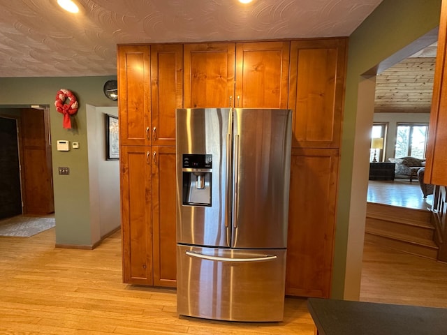 kitchen featuring brown cabinets, baseboards, light wood finished floors, and stainless steel fridge