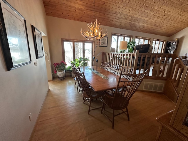 dining room with light wood-style floors, lofted ceiling, visible vents, and a notable chandelier