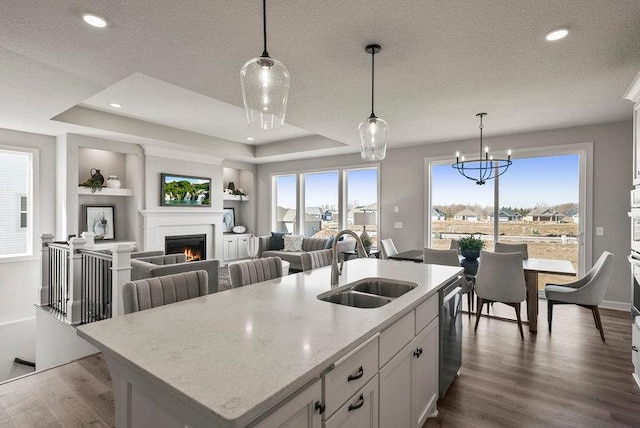 kitchen featuring an island with sink, sink, pendant lighting, and white cabinets