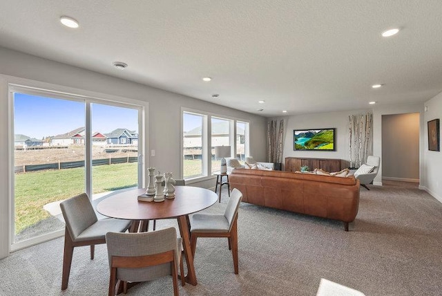 dining space with light colored carpet and a textured ceiling