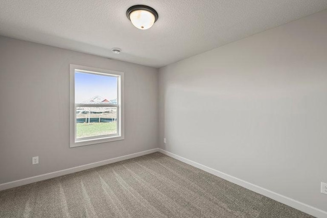 carpeted empty room featuring a textured ceiling