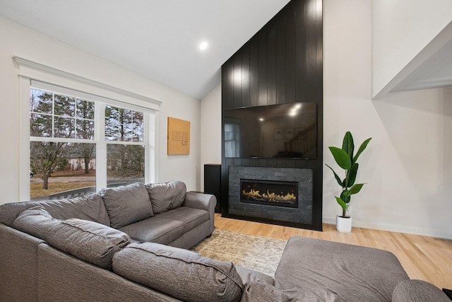 living area with high vaulted ceiling, light wood-type flooring, and a fireplace