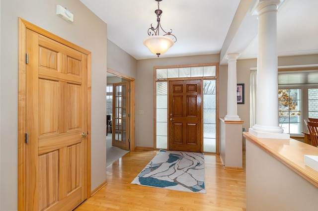 entrance foyer featuring light hardwood / wood-style flooring and ornate columns