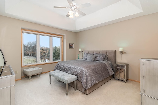 bedroom featuring light colored carpet, a raised ceiling, and ceiling fan