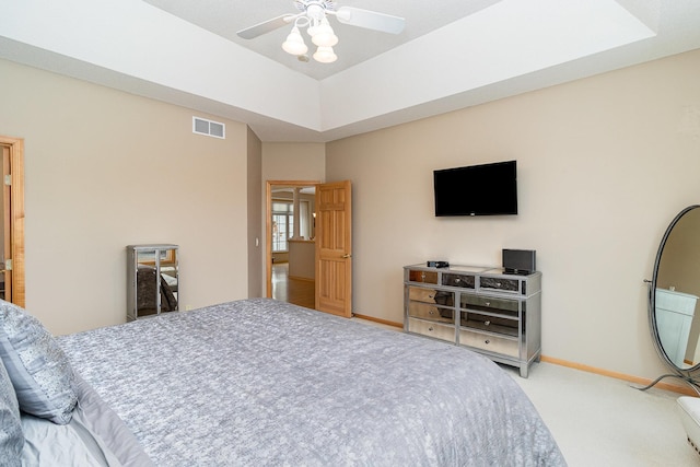 bedroom with a raised ceiling, ceiling fan, and carpet