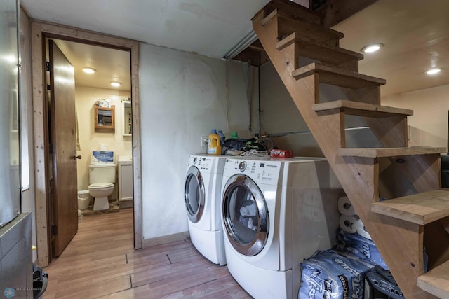 laundry area with independent washer and dryer and light hardwood / wood-style flooring