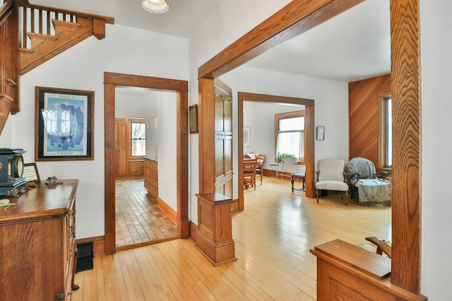 hall featuring wooden walls, a healthy amount of sunlight, and light wood-type flooring