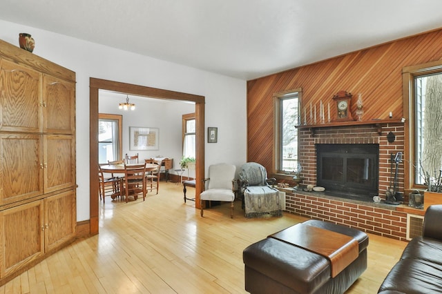 living room featuring plenty of natural light, a fireplace, light hardwood / wood-style flooring, and wood walls