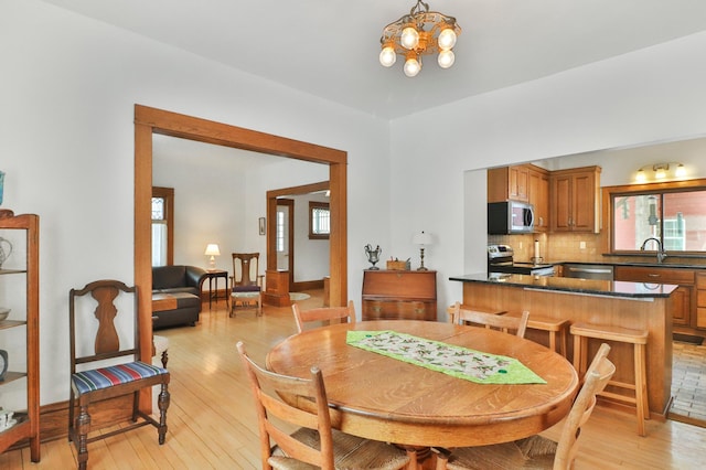 dining space featuring sink, light hardwood / wood-style flooring, a chandelier, and a healthy amount of sunlight