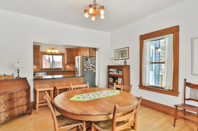 dining room with sink, an inviting chandelier, and light hardwood / wood-style floors