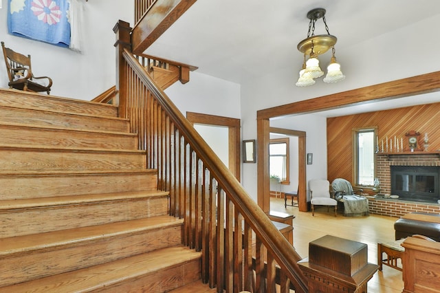 stairs with hardwood / wood-style flooring, wooden walls, and a brick fireplace