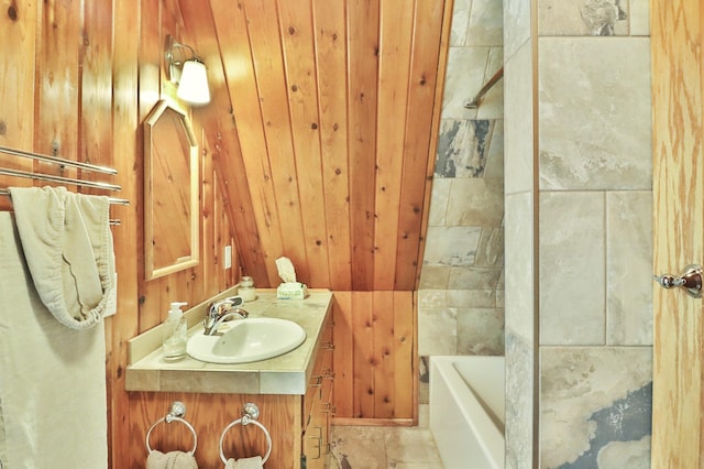 bathroom featuring vanity, a bathtub, and wooden walls