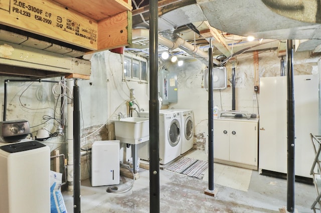 basement featuring washing machine and clothes dryer, electric panel, and sink