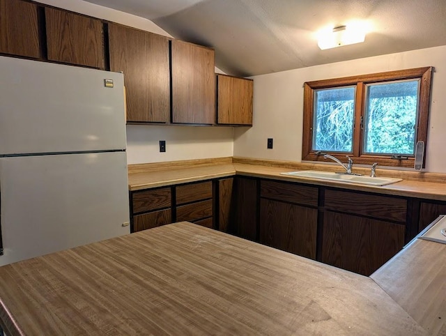 kitchen with vaulted ceiling, sink, and white fridge