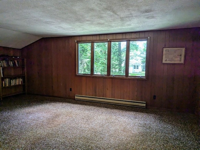 carpeted spare room with lofted ceiling, a baseboard radiator, a textured ceiling, and wood walls